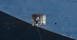  A worker performs maintenance on a large ship's side